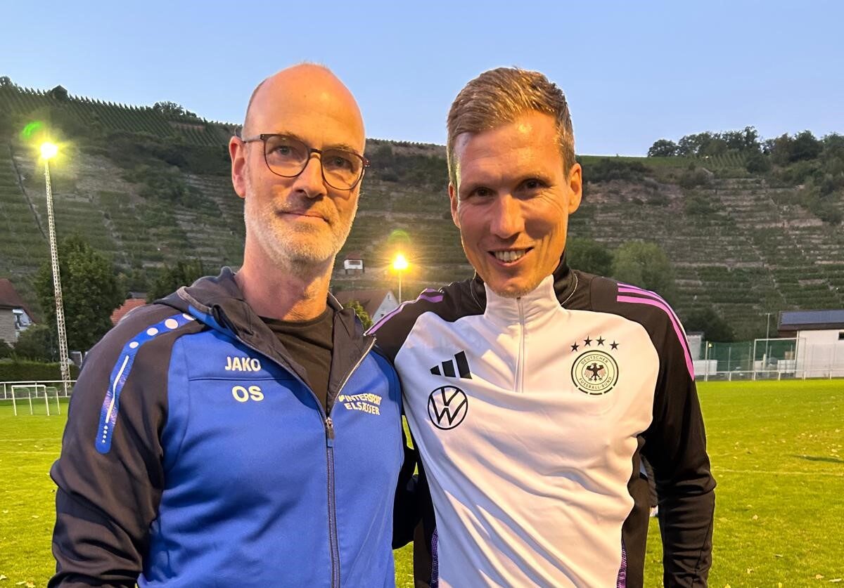 Zweier Gruppenbild lächelnd mit Spielfeld im Hintergrund bei Flutlicht